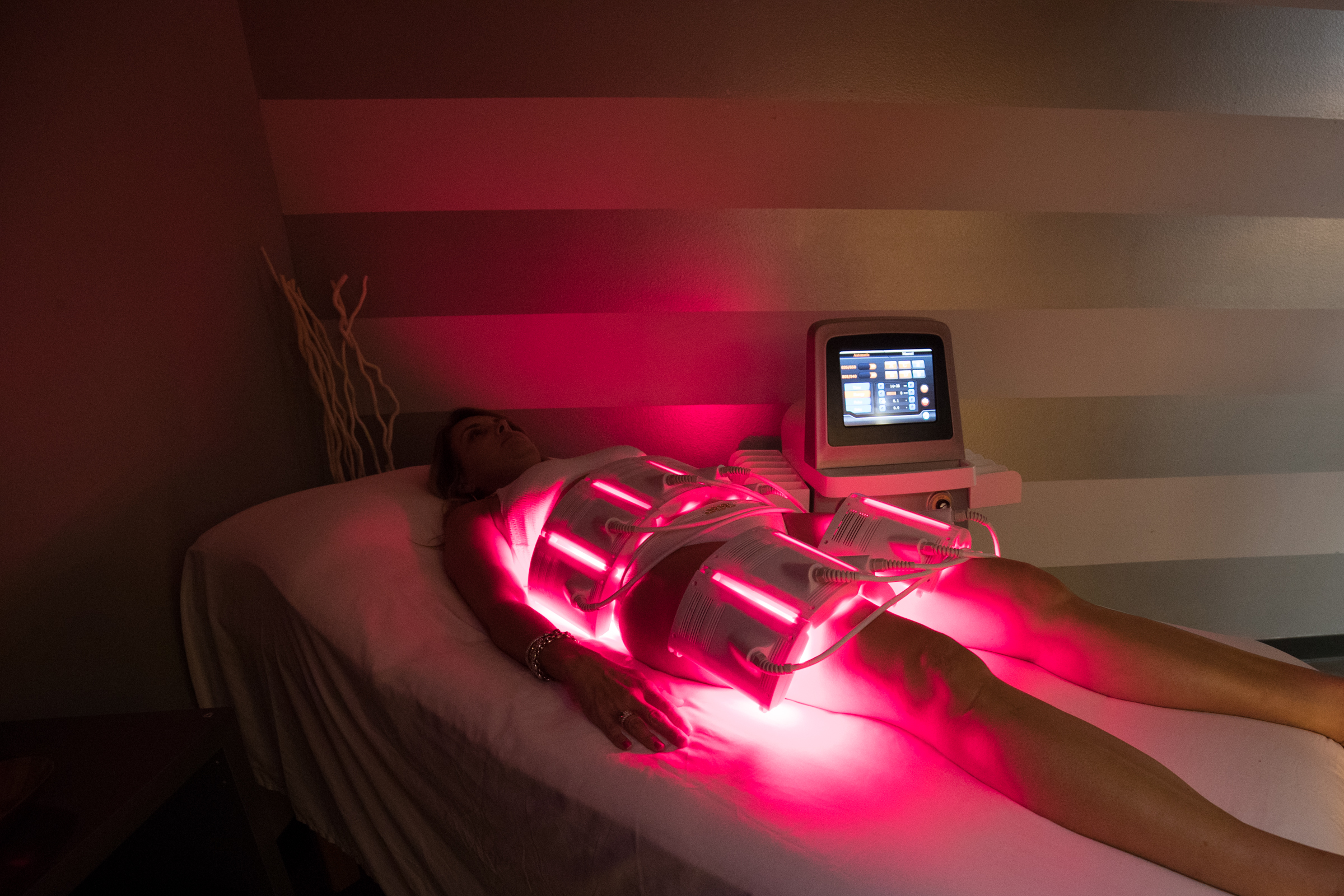 Client receiving PBM Body Pro red light body contouring therapy with glowing laser pads